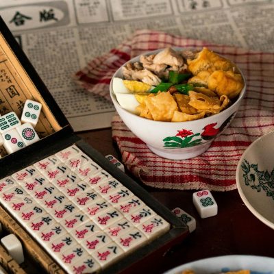 Authentic Asian dish alongside a Mahjong game set, evoking a cultural dining experience.