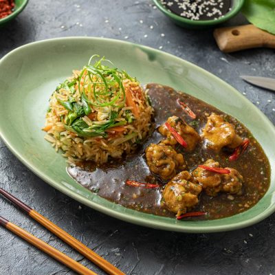Tasty and spicy Asian dish with fried meat and vegetables on an oval plate, perfect for gourmet dining.